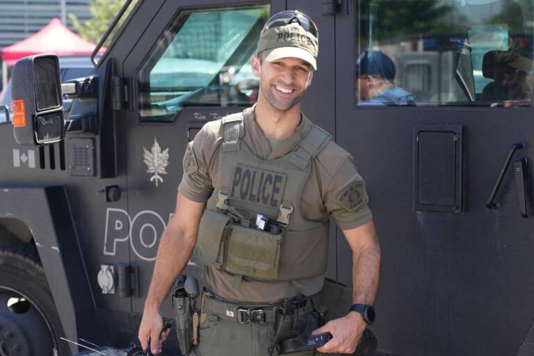 CBSA officer in tactical gear standing beside an armored vehicle during a public event