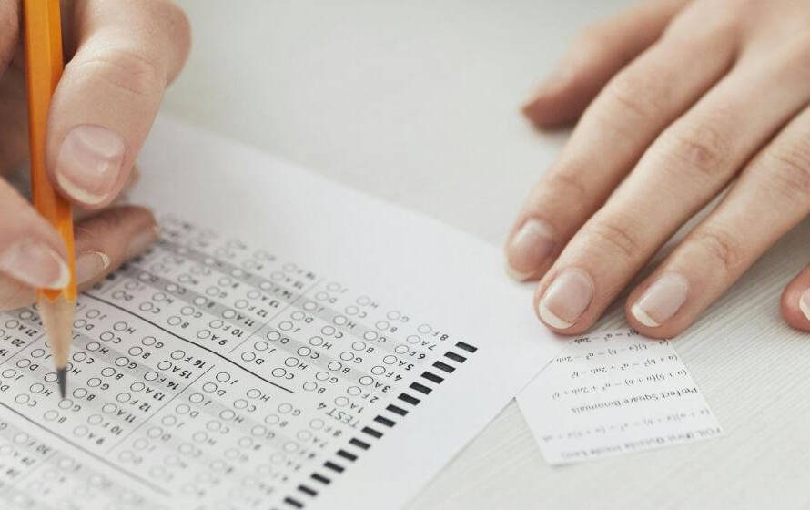 Person filling out a multiple-choice test sheet with a pencil, representing CBSA behavioural interview preparation