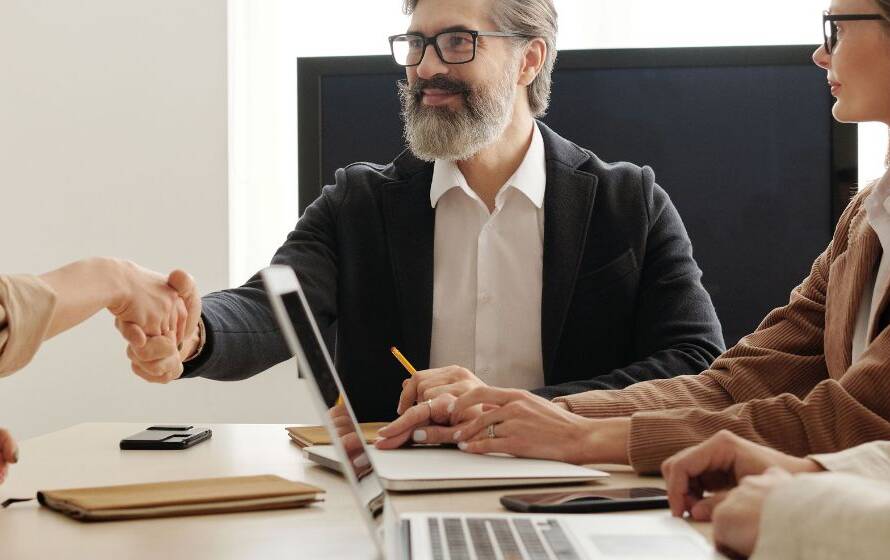 Job candidate shaking hands with a hiring manager during an interview, representing recruitment, employment opportunities, and the impact of hiring freezes on CBSA applicants.