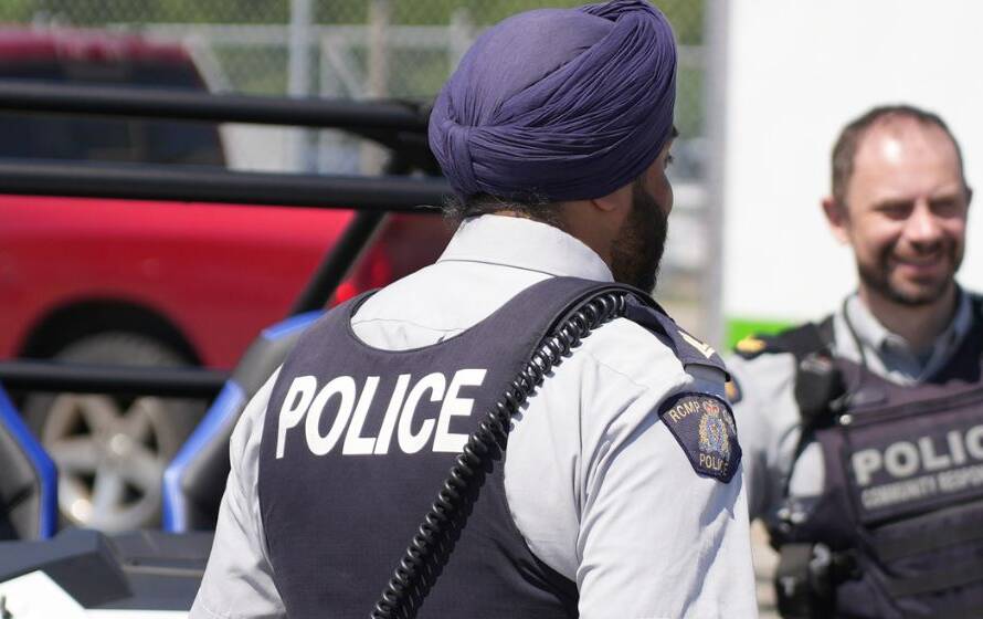 Two law enforcement officers standing beside a patrol vehicle near a waterfront or port facility, representing border security operations, marine patrols, and cross-agency enforcement activities.