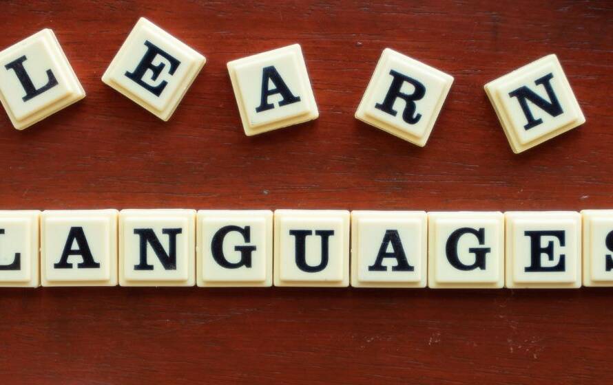 Letter tiles spelling "Learn Languages" on a wooden desk, representing bilingualism, French language proficiency, and language training opportunities for CBSA employees.