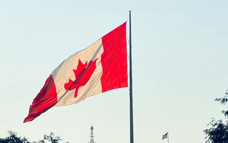 Canadian flag flying outside a modern government building, representing Canadian citizenship, immigration status, and eligibility requirements for federal law enforcement careers.