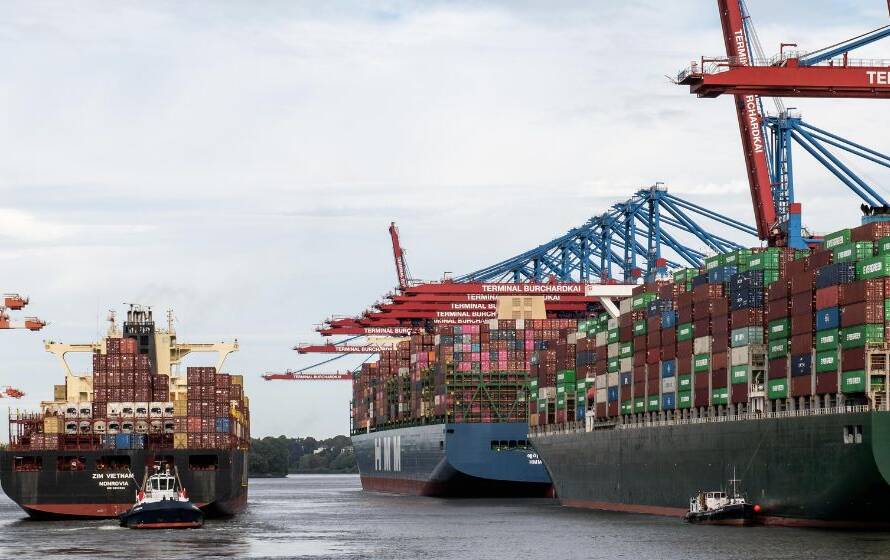 Large container ships docked at an international port, surrounded by cargo cranes and stacked shipping containers, illustrating global trade and overseas CBSA operations.