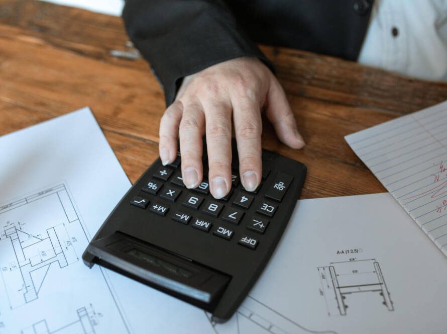 CBSA Overtime and Shift Premiums, salary guide - Hand using calculator for architectural calculations on blueprints
