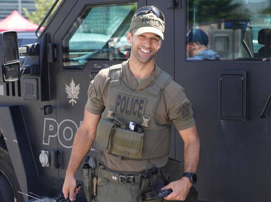 CBSA officer in tactical gear standing beside an armored vehicle during a public event