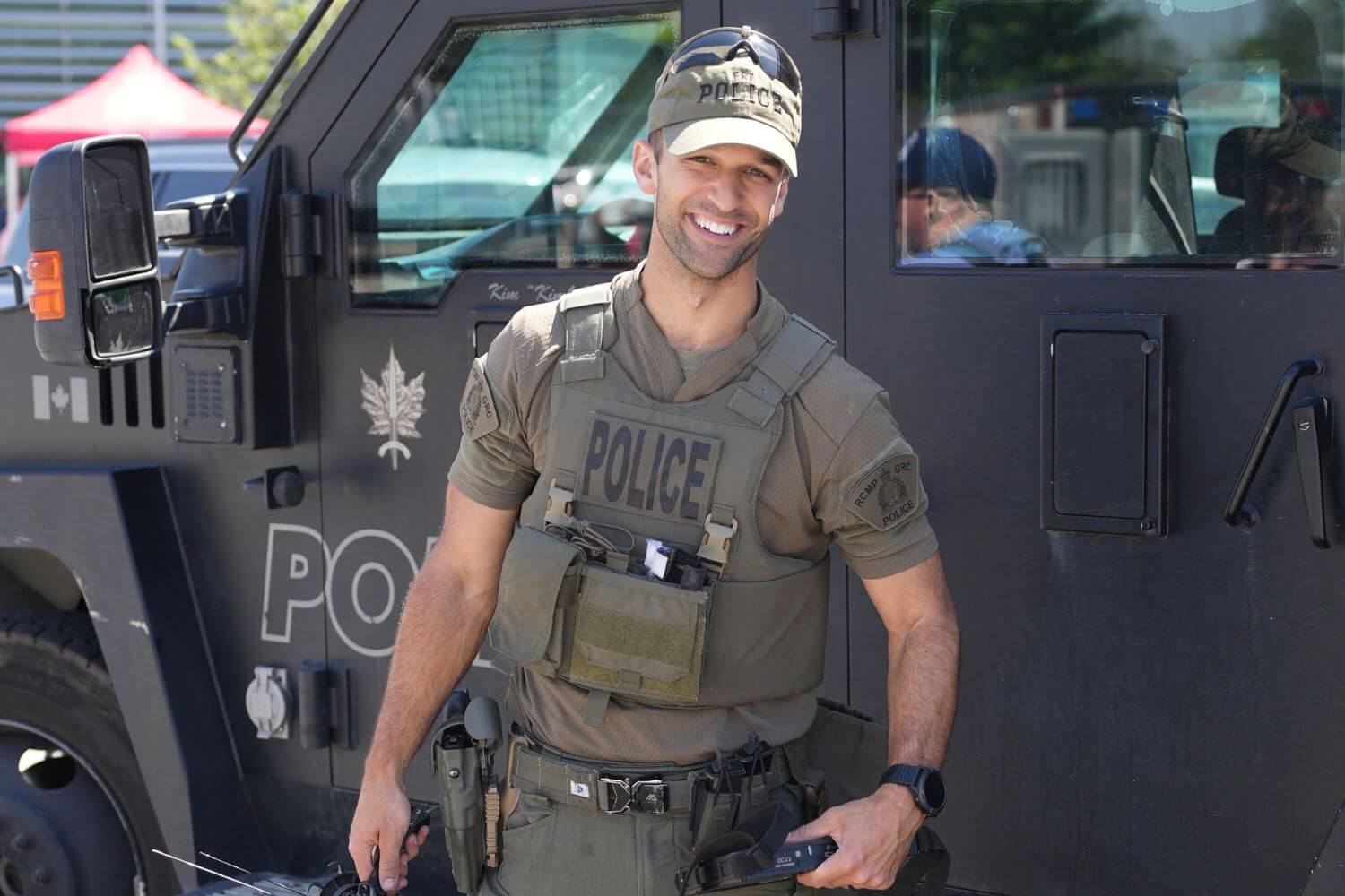 CBSA officer in tactical gear standing beside an armored vehicle during a public event