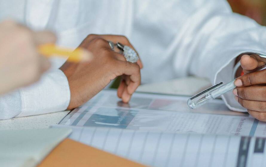 Two employees reviewing documents and discussing paperwork at a desk, representing professional development, temporary leadership roles, and acting assignments within the Canada Border Services Agency.