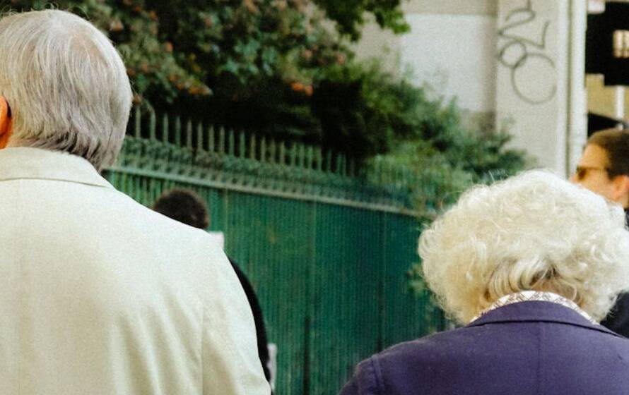 Older adults walking together in a public urban setting, representing retirement planning, family financial security, survivor benefits, and long-term pension protection.
