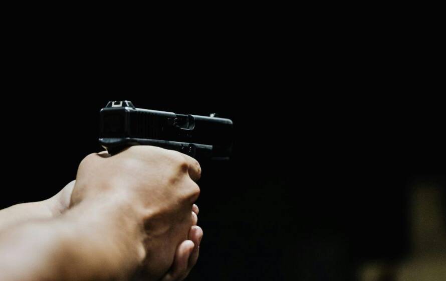 Close-up image of an individual holding a handgun in a controlled training environment, representing firearms proficiency, use-of-force training, and law enforcement readiness.