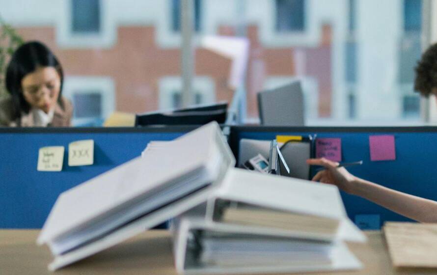 Office professionals working in a modern administrative environment, handling documents, phone calls, and computer-based tasks in a collaborative workplace.