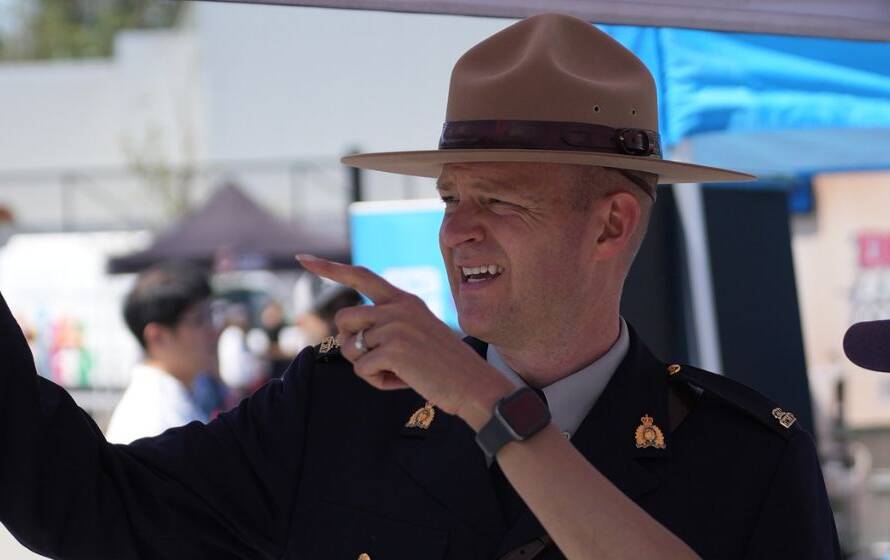 RCMP officer in uniform speaking with a member of the public at a community outreach event, illustrating law enforcement recruitment, public engagement, and career information services in Canada.