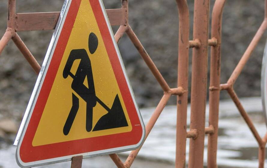 Road construction and restricted-access signs positioned behind a barrier, symbolizing challenging work environments, controlled access areas, operational restrictions, and field-based responsibilities.