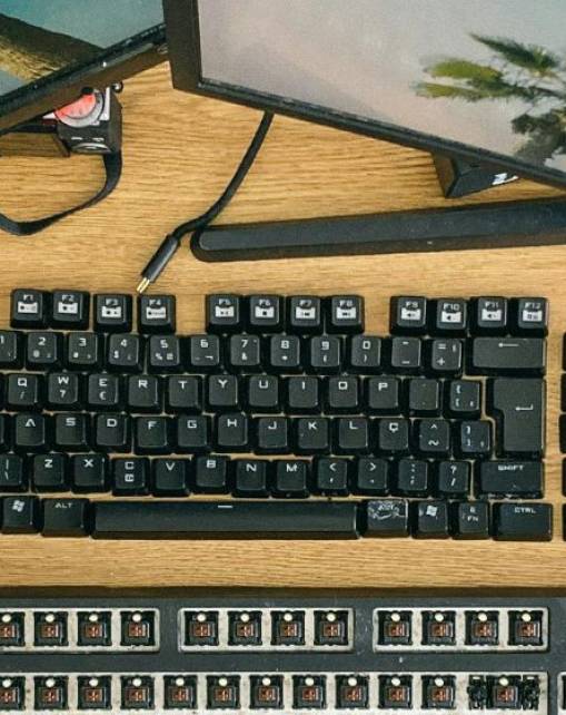 Desktop workstation with multiple computer monitors, keyboards, and office equipment, representing digital application processing, candidate screening, and administrative evaluation systems used during recruitment.